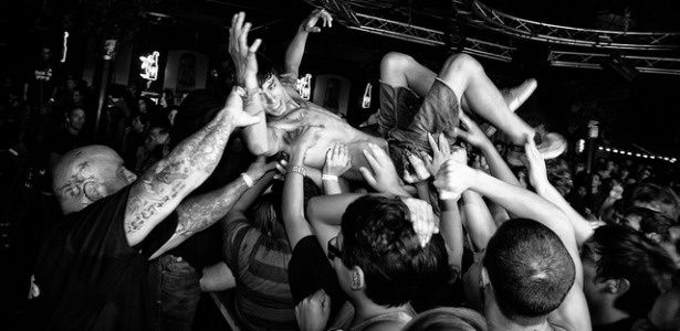 Concertgoers lift a crowd surfer above a tightly packed mosh pit