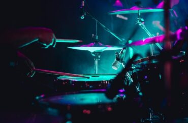 Close-up of a drummer playing a kit under vivid concert lights