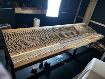Large analog mixing console inside a dimly lit recording studio