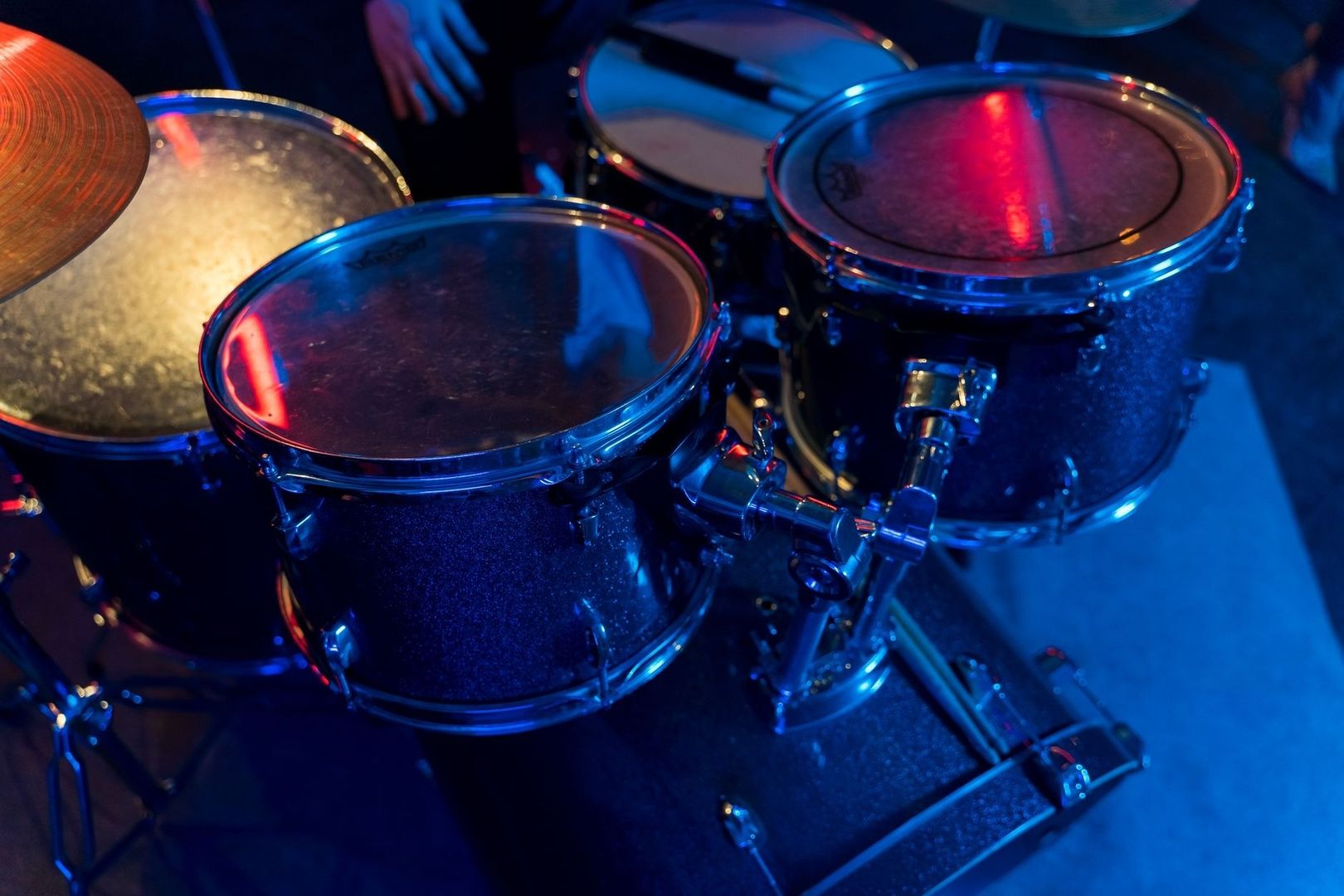 Close-up of a drum kit glowing under blue and red stage lights