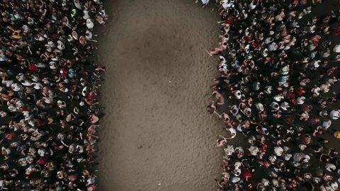 Aerial view of two dense crowds separated by an open dirt corridor