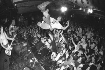 Punk vocalist dives over a tightly packed crowd during a live show